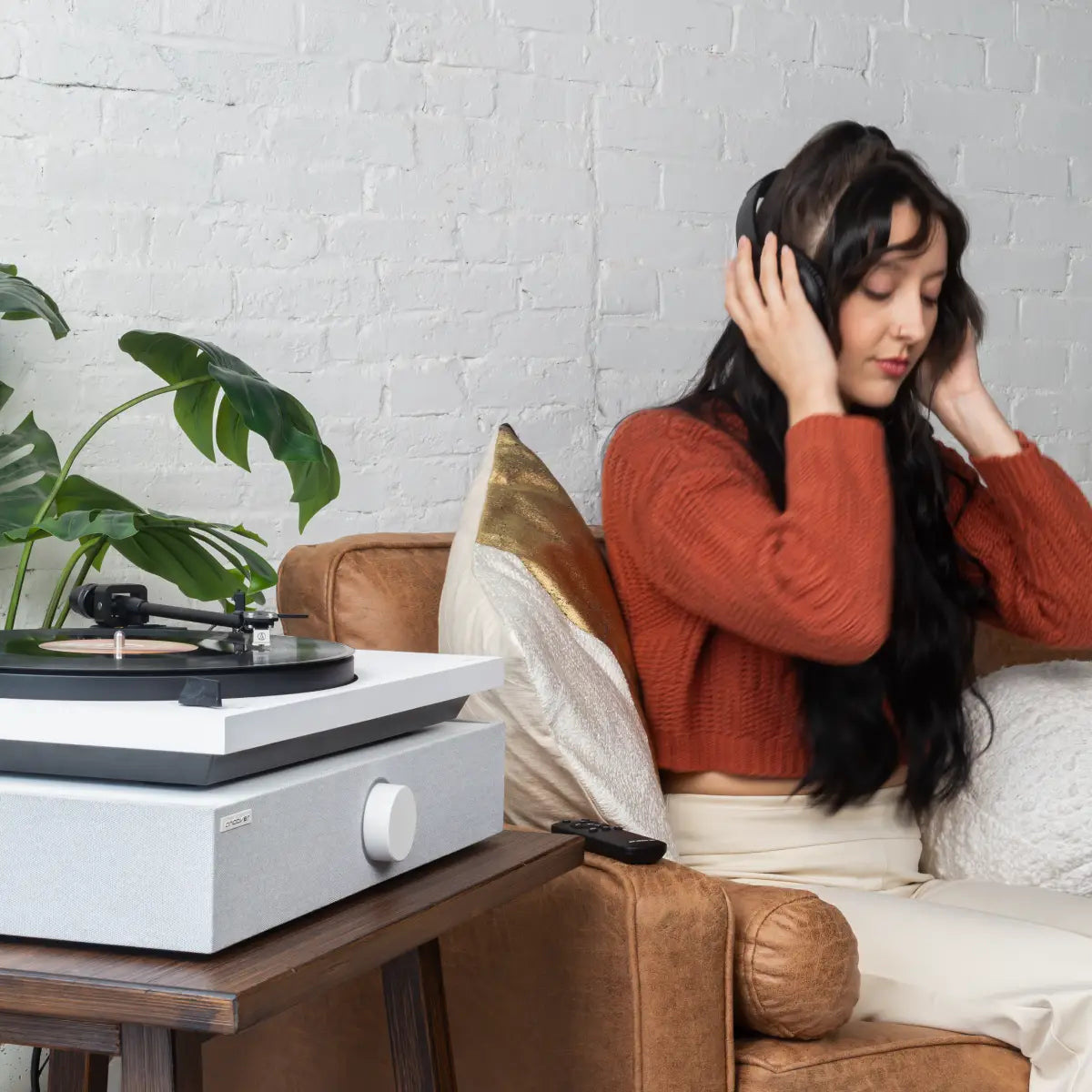 Listener wearing headphones beside a white SpinBase 2 and turntable.