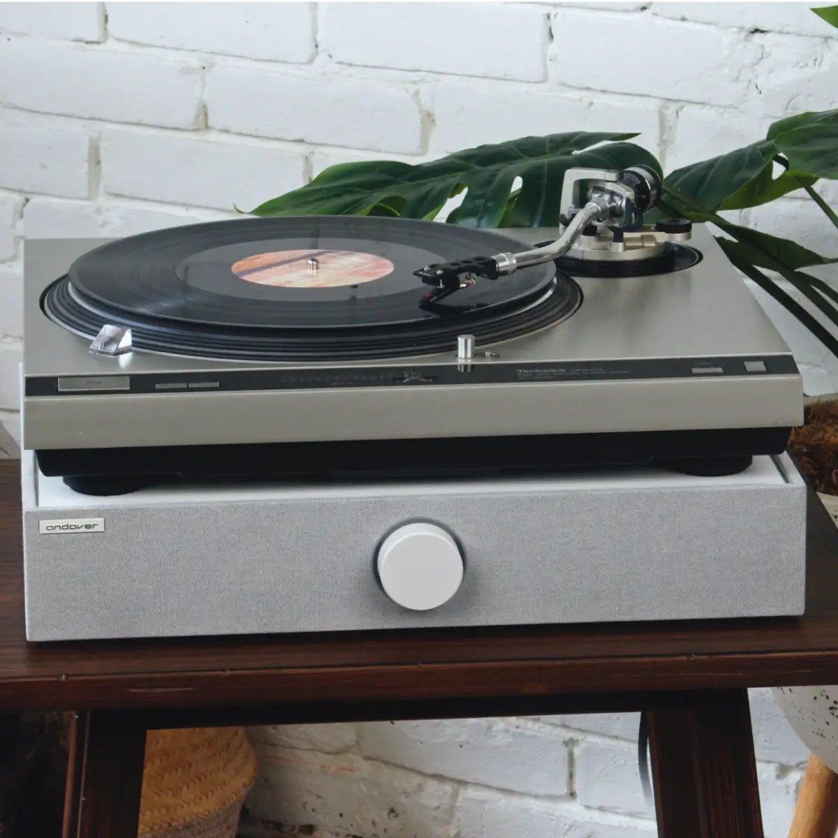 Vintage-style turntable playing a record directly above a white SpinBase 2.