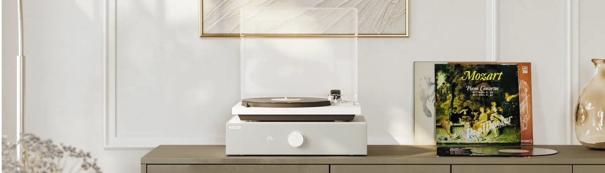 White SpinBase MAX 2 supporting a turntable beside a displayed record sleeve.