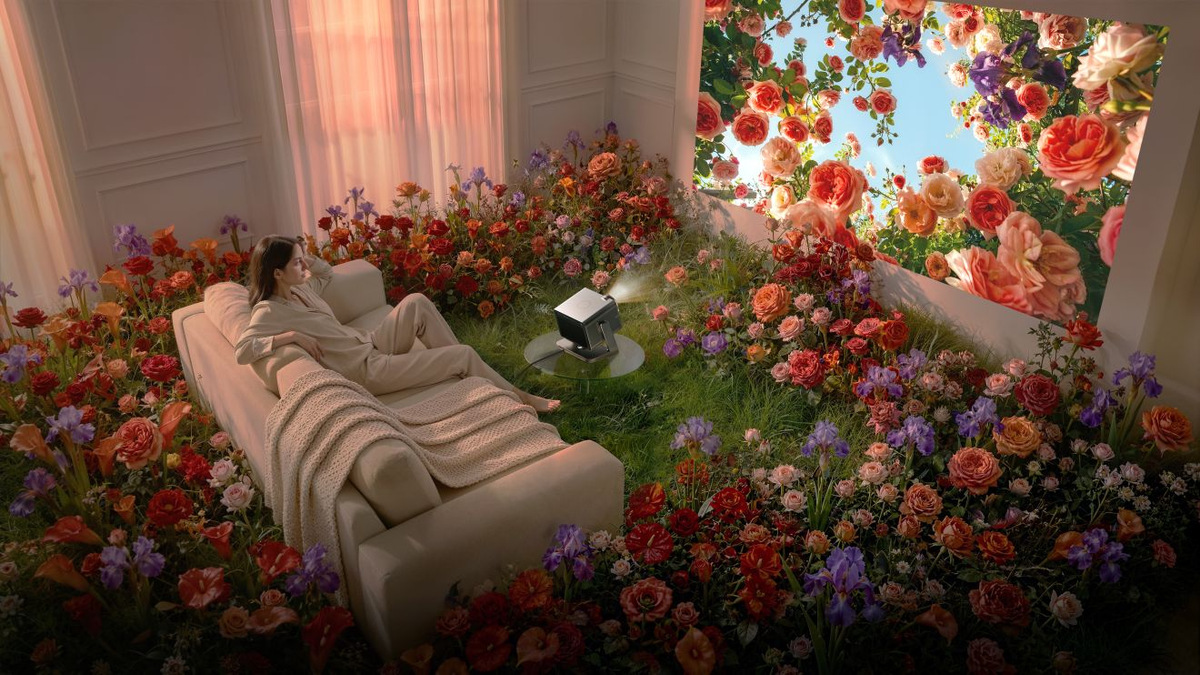 Viewer reclining in a flower-filled room while the projector displays colourful flowers on the wall.