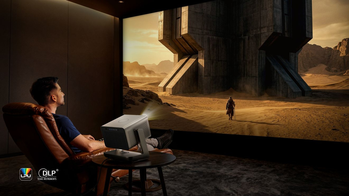 Viewer seated beside a Hisense C3 Ultra watching a projected science-fiction desert scene.