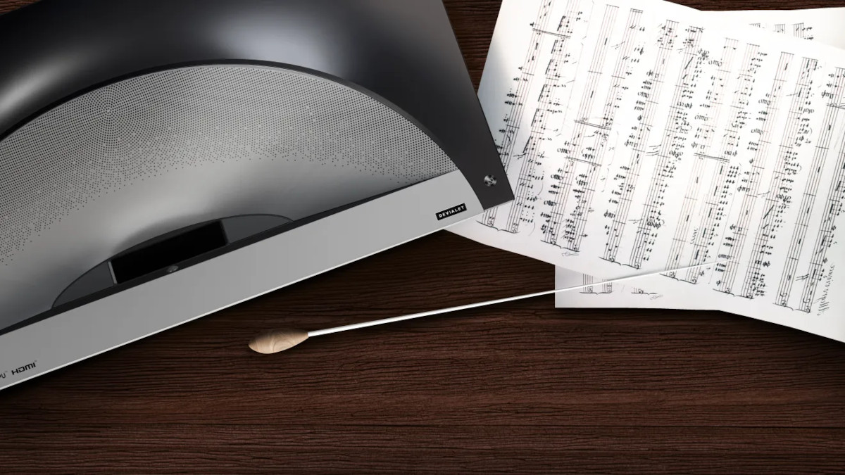 Close-up of the Hisense PX4 Pro speaker grille beside sheet music and a conductor’s baton.